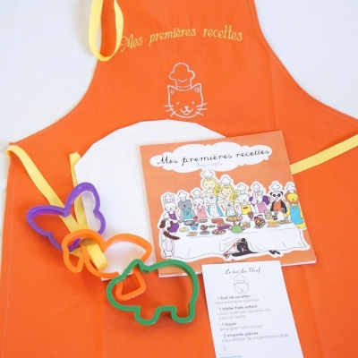 Kit du chef Mes premières recettes de Delphine Dumont  Editions Plumes et Confettis Couverture du livre sur fond orange, 3 emporte-pièces à sablés vert, orange et violet sont posés sur un tablier orange et une toque en papier blanche à colorier.