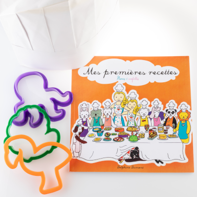 Kit du cordon bleu Mes premières recettes Couverture du livre sur fond orange, 3 emporte-pièces à sablés vert, orange et violet et une toque en papier blanche à colorier.